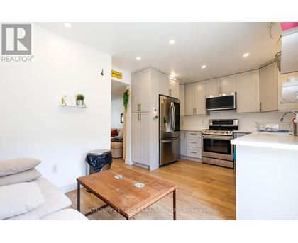 A modern kitchen with wooden floors and stainless steel appliances.