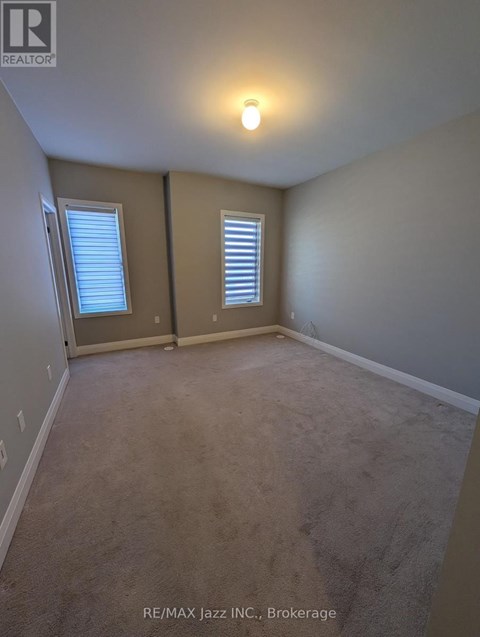 A room with a carpeted floor and two windows.
