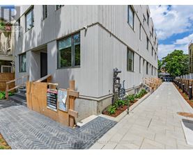 A modern building with a wooden fence and a sign on the sidewalk.