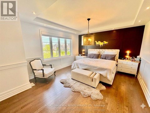 A bedroom with a large bed, a chair, and a window.
