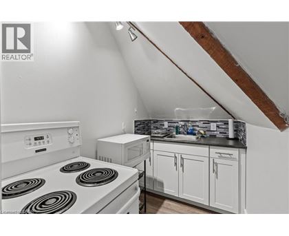 A white stove top oven in a kitchen with a microwave and a sink.