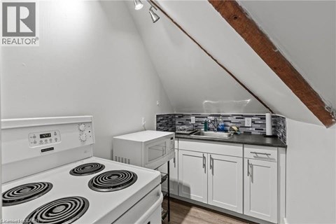 A white stove top oven in a kitchen with a microwave and a sink.