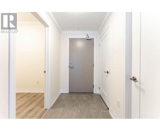 A hallway with a door at the end and a broker logo on the wall.