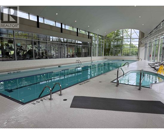 A large indoor swimming pool with a black mat on the floor.