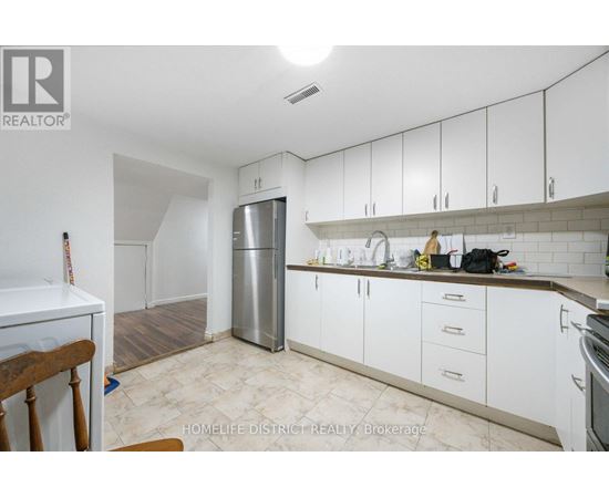 A kitchen with white cabinets and a stainless steel refrigerator.