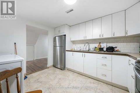 A kitchen with white cabinets and a stainless steel refrigerator.
