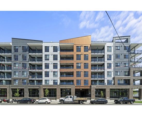 A modern multi-story building with a parking lot in front.