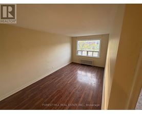 A room with wooden flooring and a window with a view of trees.