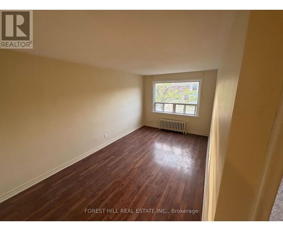 A room with wooden flooring and a window with a view of trees.