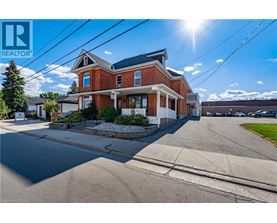 A large red brick house with a white trim and a sunny sky above.