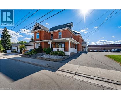 A large red brick house with a white trim and a sunny sky above.
