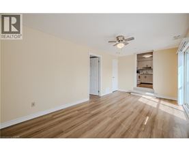 A spacious room with wooden flooring and a ceiling fan.