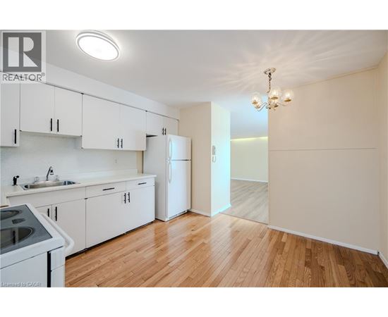 A kitchen with white cabinets and a wooden floor.