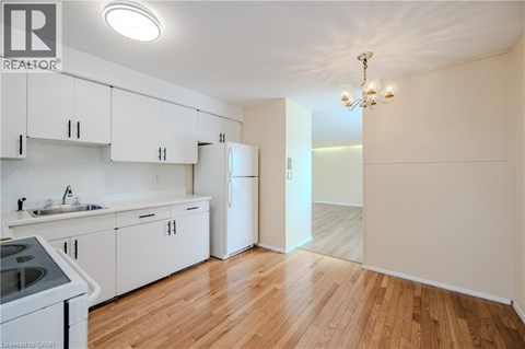 A kitchen with white cabinets and a wooden floor.