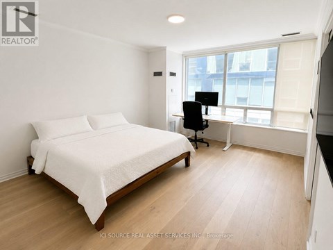 A bedroom with a bed, desk, and chair.