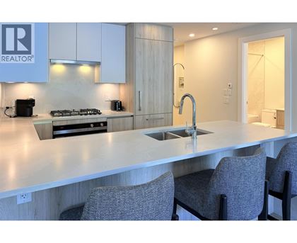 A modern kitchen with a large island and grey chairs.