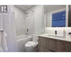 A white toilet sits in a bathroom with a white tub and sink.