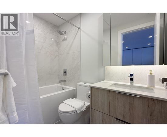 A white toilet sits in a bathroom with a white tub and sink.