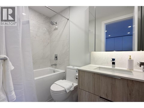 A white toilet sits in a bathroom with a white tub and sink.