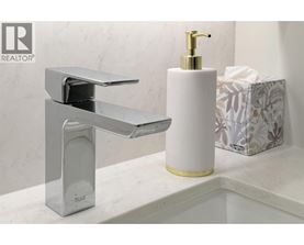 A modern bathroom sink with a chrome faucet and a white soap dispenser.