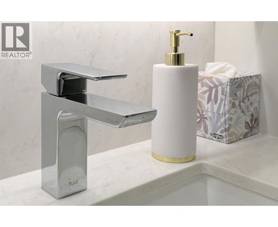 A modern bathroom sink with a chrome faucet and a white soap dispenser.