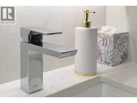 A modern bathroom sink with a chrome faucet and a white soap dispenser.