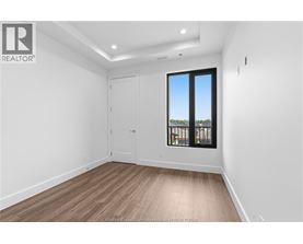 A room with a wooden floor and a large window with a view of trees outside.
