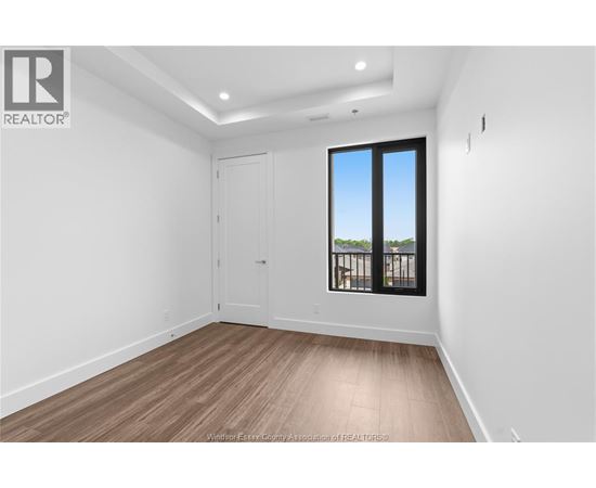 A room with a wooden floor and a large window with a view of trees outside.