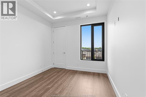 A room with a wooden floor and a large window with a view of trees outside.