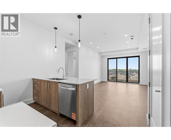 A modern kitchen with wooden cabinets and a large window.