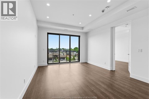 A spacious room with a view of a balcony with a railing.