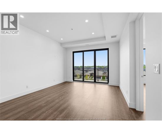 A spacious room with a view of a balcony with a railing.