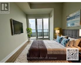 A bedroom with a large bed, a flat screen TV, and a window with a view of the ocean.