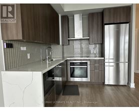 A modern kitchen with a refrigerator, oven, and sink.