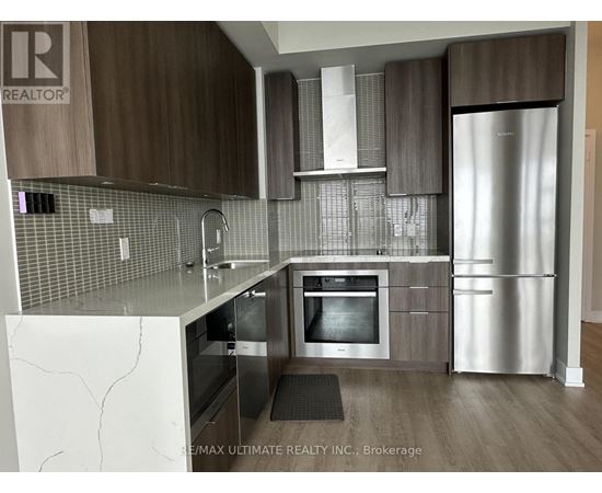 A modern kitchen with a refrigerator, oven, and sink.