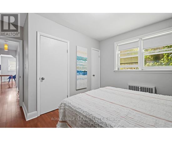 A bedroom with a large bed and a window with blinds.