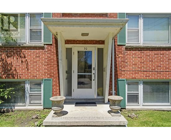 A red brick house with a white door and a stone planter in front.