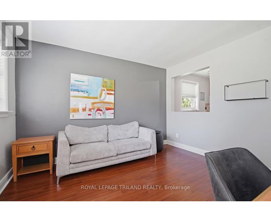 A living room with a grey couch and a painting on the wall.