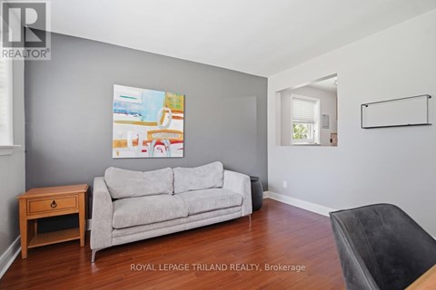 A living room with a grey couch and a painting on the wall.