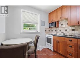 A small kitchen with brown chairs and a white oven.