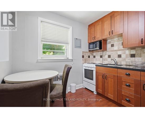 A small kitchen with brown chairs and a white oven.