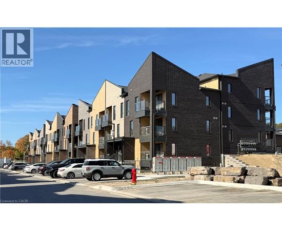 A row of modern apartment buildings with cars parked in front.