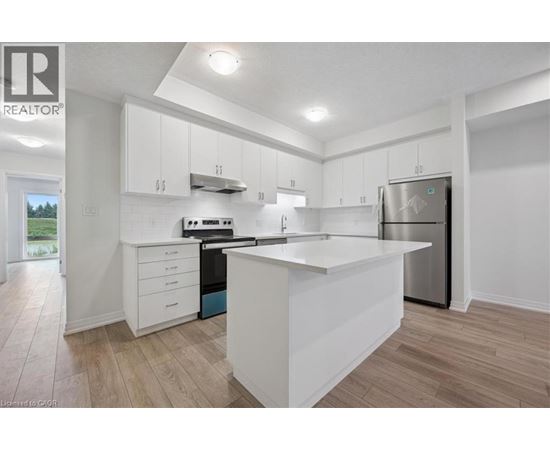 A modern kitchen with white cabinets and a wooden floor.