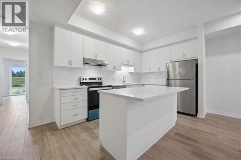 A modern kitchen with white cabinets and a wooden floor.