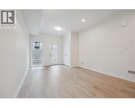 A spacious room with wooden flooring and white walls.