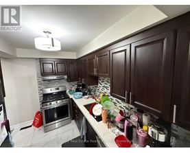 A kitchen with dark wood cabinets and a stainless steel stove top.