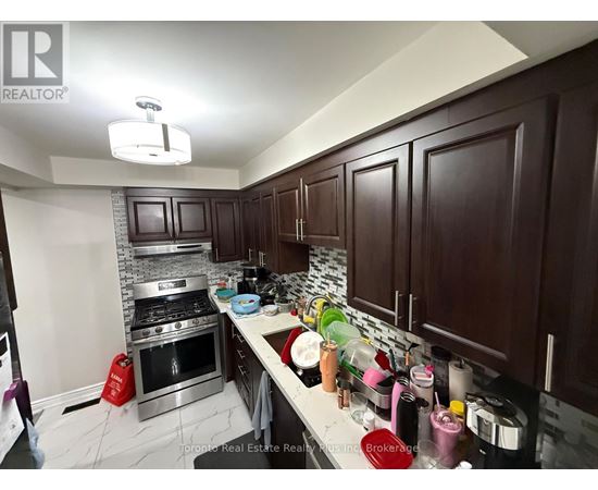 A kitchen with dark wood cabinets and a stainless steel stove top.