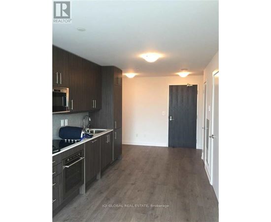A kitchen with dark wood cabinets and a black door.
