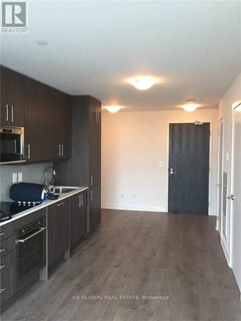 A kitchen with dark wood cabinets and a black door.