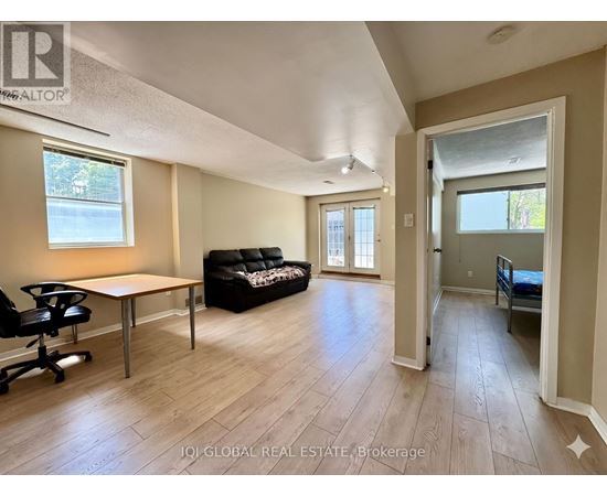 A spacious living room with a black couch and a wooden table.